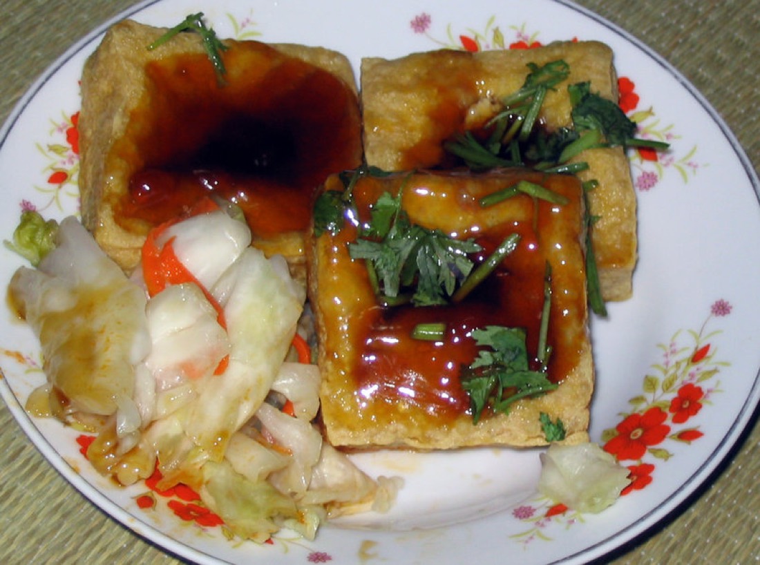炸臭豆腐方块，顶端凹陷盛着酱汁，配上泡菜