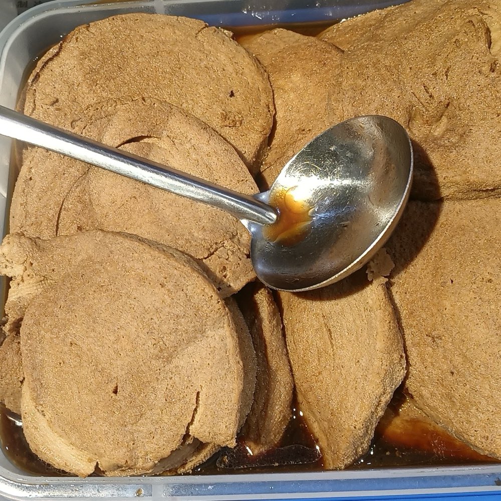 切片的酱卤素鸡圆片泡在卤汁里，旁边有一把杓子